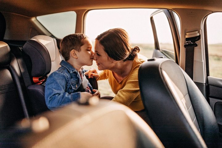 En kvinna pussar ett barn i en bil